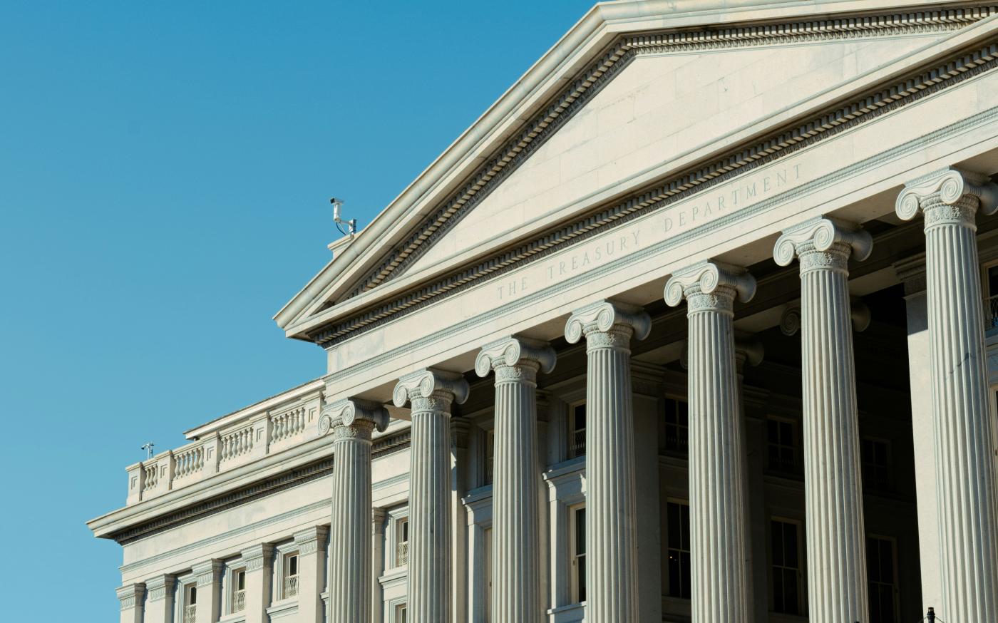 a large white building with a flag on top of it by Vincent Yuan @USA courtesy of Unsplash.