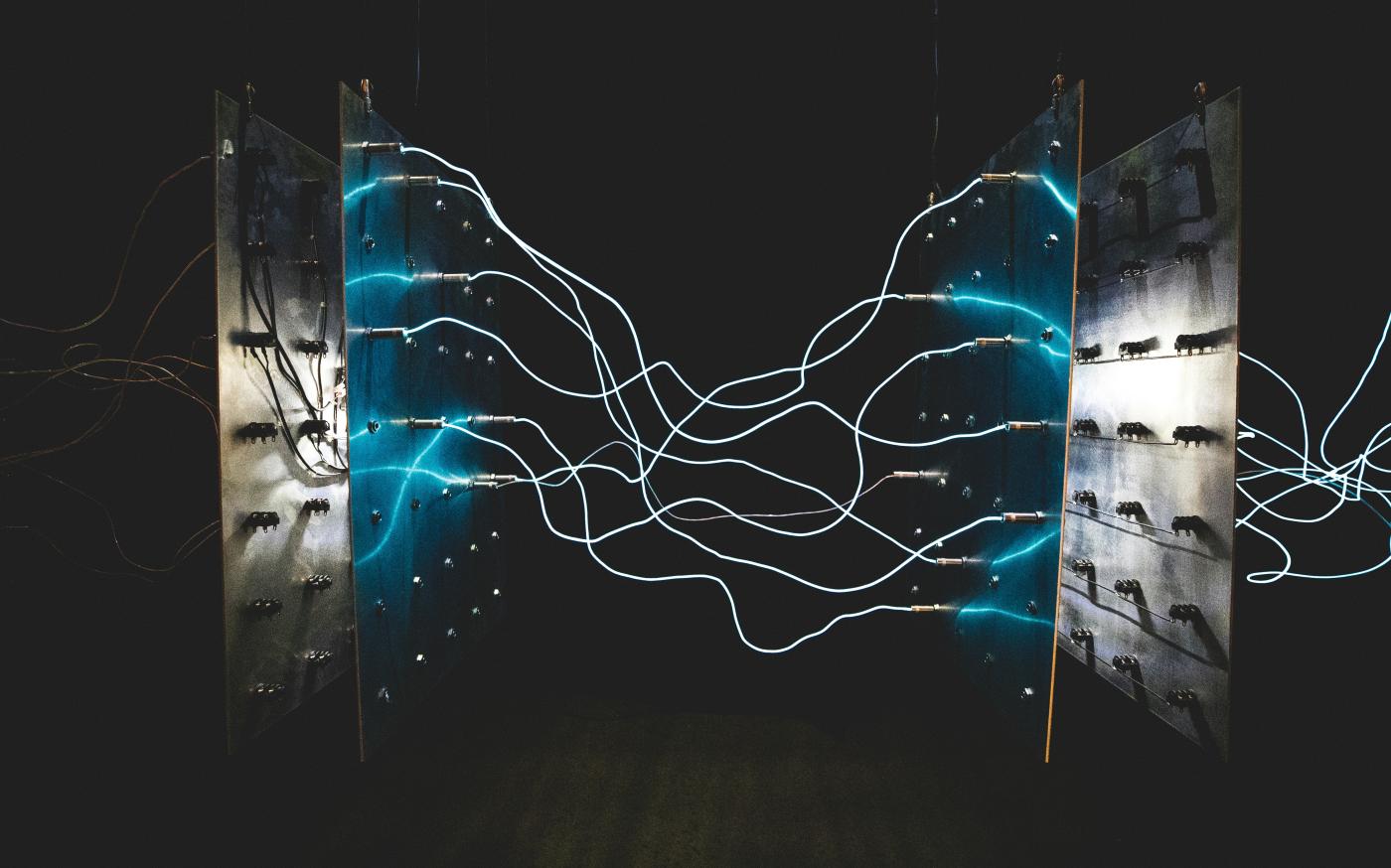 Bright blue electrical arcs connecting two metal panels against a dark background by israel palacio courtesy of Unsplash.
