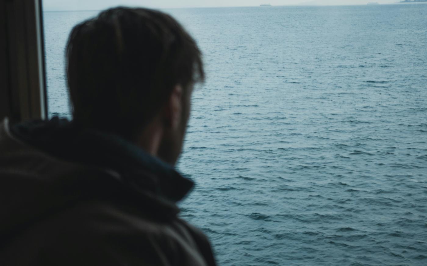 man standing near calm ocean by Sylas Boesten courtesy of Unsplash.