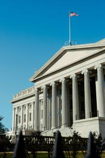 a large white building with a flag on top of it by Vincent Yuan @USA courtesy of Unsplash.
