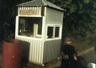 Man in uniform sits by guardhouse with sign. by Illia Horokhovsky courtesy of Unsplash.