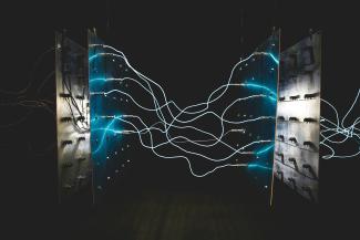 Bright blue electrical arcs connecting two metal panels against a dark background by israel palacio courtesy of Unsplash.