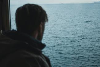 man standing near calm ocean by Sylas Boesten courtesy of Unsplash.