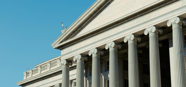 a large white building with a flag on top of it by Vincent Yuan @USA courtesy of Unsplash.