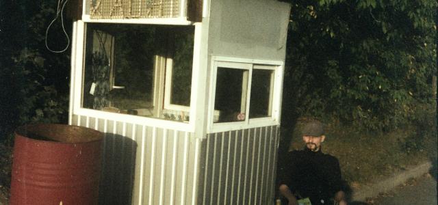 Man in uniform sits by guardhouse with sign. by Illia Horokhovsky courtesy of Unsplash.