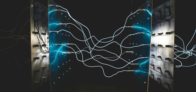 Bright blue electrical arcs connecting two metal panels against a dark background by israel palacio courtesy of Unsplash.