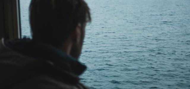 man standing near calm ocean by Sylas Boesten courtesy of Unsplash.